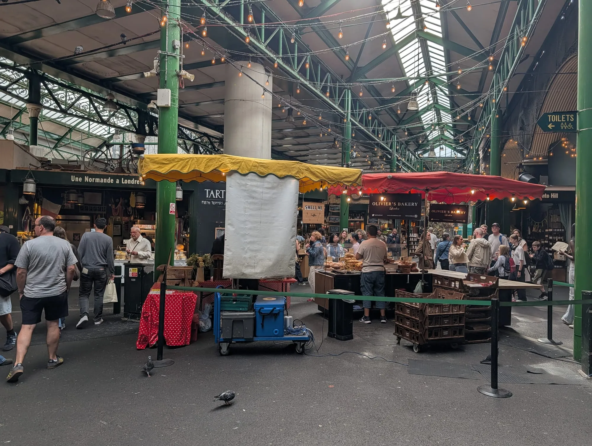 Traders and shoppers under the green ironwork and festoon lights of Borough Market