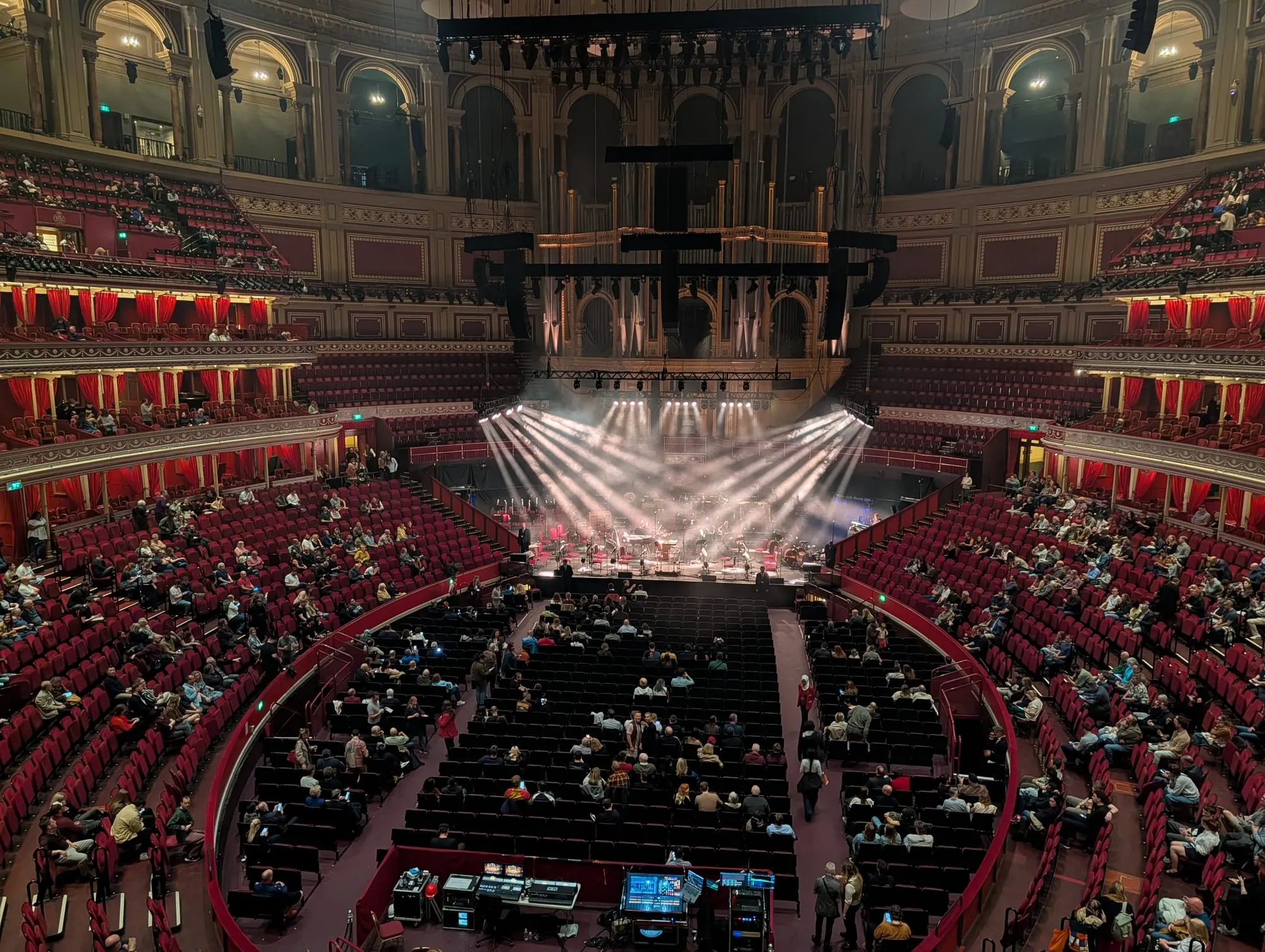 The Royal Albert Hall auditorium during a concert, tiers of red seating curving around a lit stage